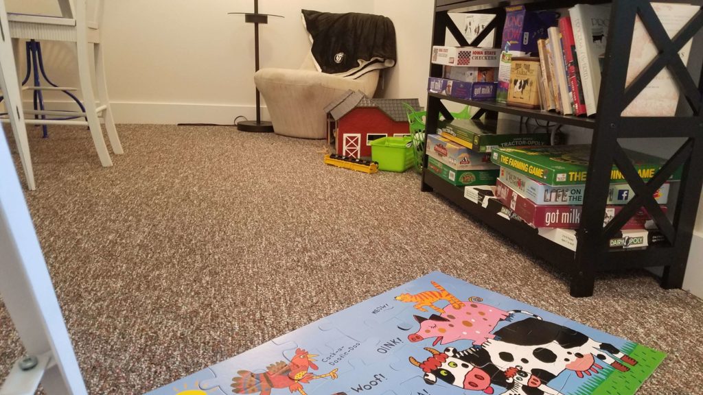 Puzzle on the floor with shelf full of games, DVD, and books behind it with a chair in the background