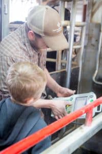 man and boy with robot milking controller