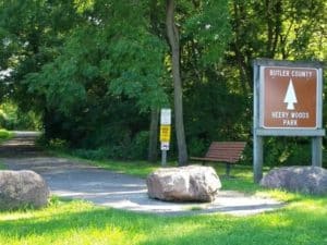 Sign for bike trail and park with trail leading into woods