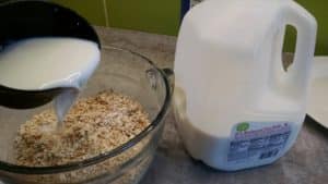 pouring milk into big bowl of oatmeal