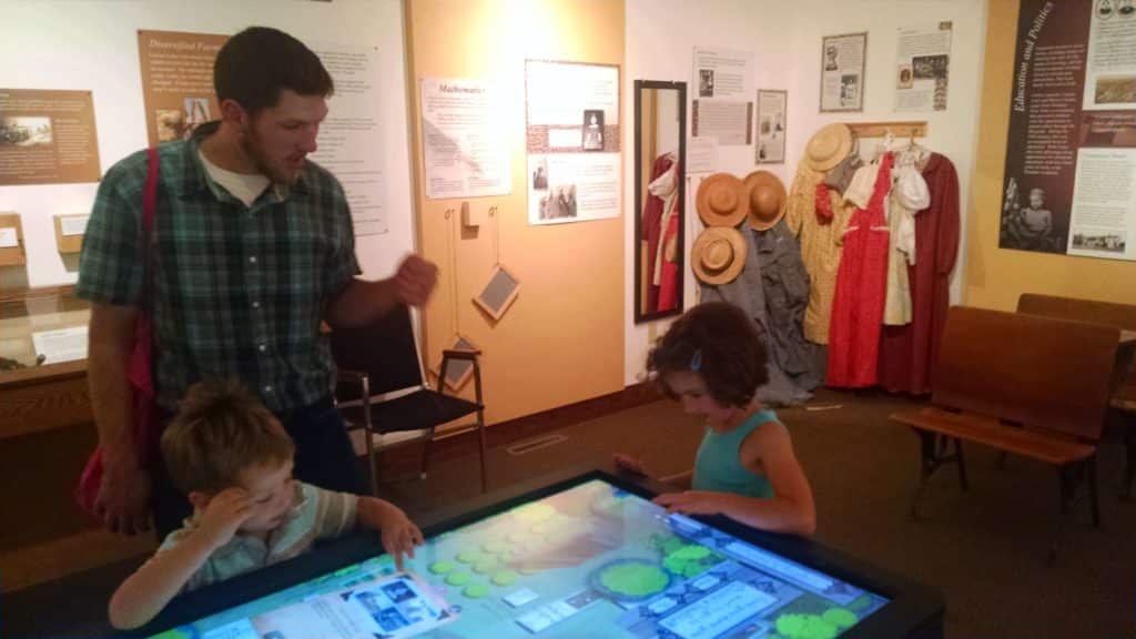 kids and dad in a museum playing a interactive touch screen table