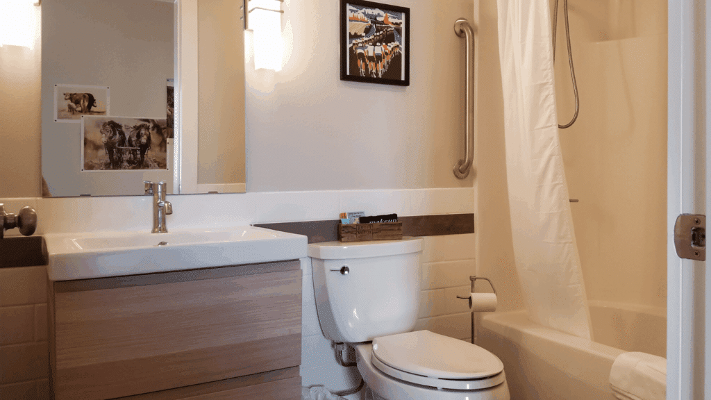 Modern bathroom with light wood vanity, white sink, toilet, and shower-tub combo with white curtain and wall art above