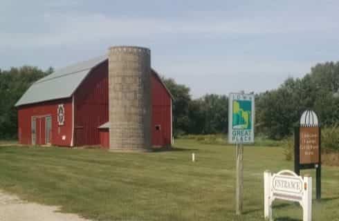 Large red barn with gray silo sitting in a field of green grass