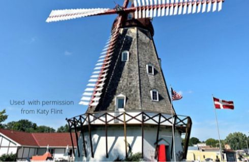 Large windmill house with white painted walls and gray wood slats on top