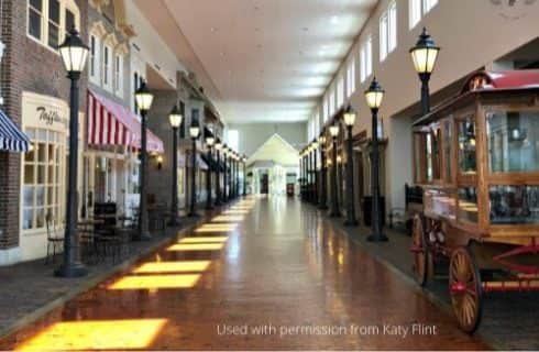 Long corridor of small store fronts and street lights inside a large building