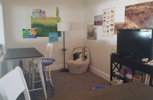 room with 2 pub tables, chair and console holding TV & games & puzzles