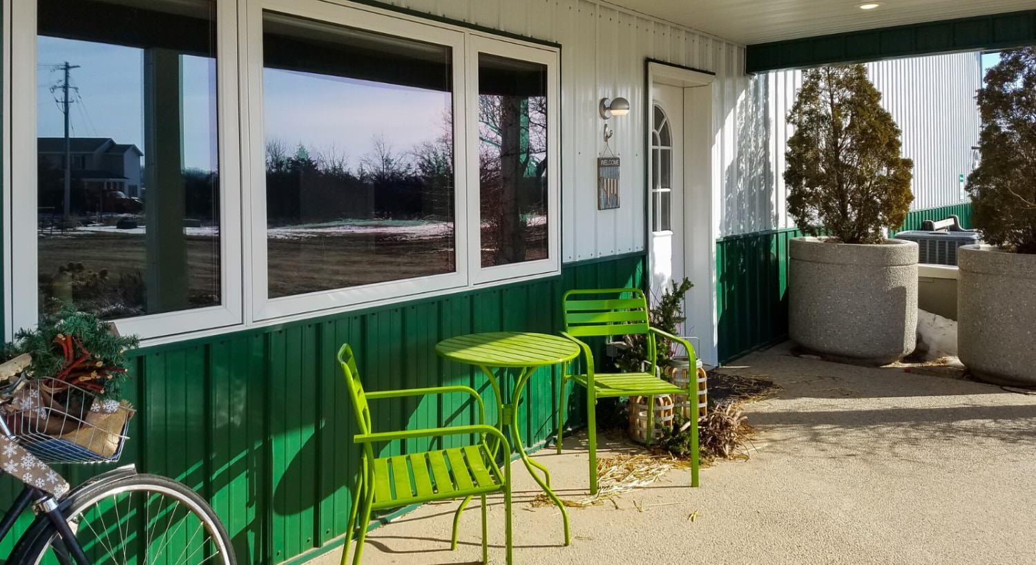 View from patio outside of the property painted green and white with a green table and green chairs