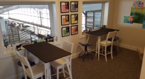 Room with wooden tables and chairs with windows overlooking dairy cow operations