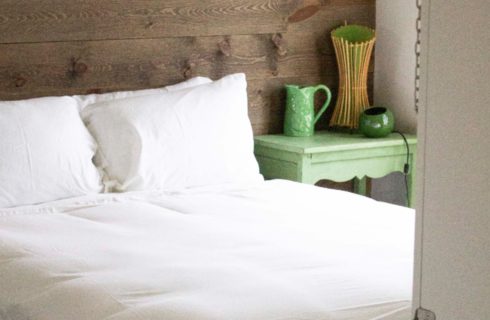 bed with white sheets with a green side table with green lamp