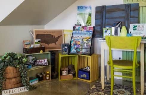 Multiple wooden milk crates painted yellow and green filled with many different types of items that are for sale